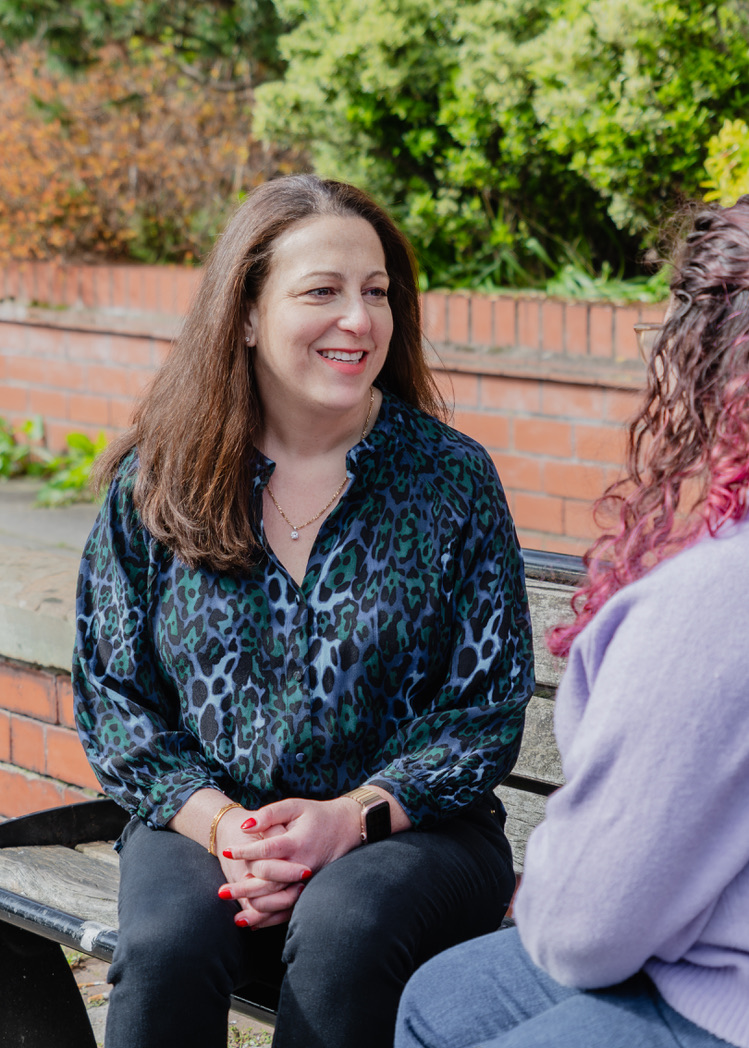 Hannah Cohen in conversation with a client on a bench outdoors